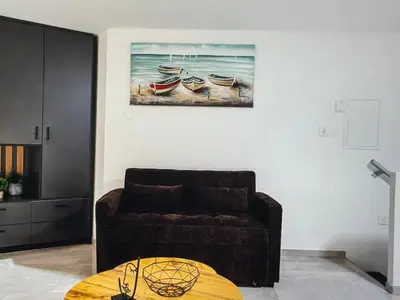 a living room with a couch and a painting of three boats at Super Views Larnaca in Larnaka