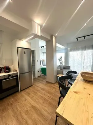 a kitchen and living room with a table and a refrigerator at Zeus Downtown Hub with Panoramic View in Nicosia