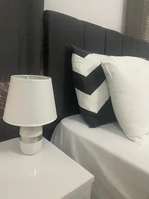 a lamp on a table next to a bed with pillows at Famagusta Guest House in Mağusa