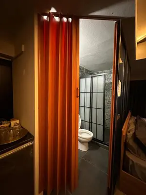 an orange shower curtain in a bathroom with a toilet at Centrally located studio with Mountain & Sea views in Avdhelleron