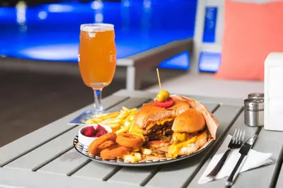 a plate of food with a sandwich and chips and a drink at Kıbrıs Girnede 1 yatak odalı Süper lüks havuzlu daire in Vuda