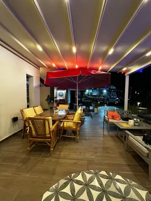 a dining room with a table and chairs and an umbrella at Kıbrıs Girnede 1 yatak odalı Süper lüks havuzlu daire in Vuda
