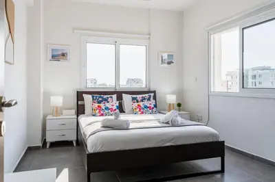 a bedroom with a bed with white walls and windows at Sonic 2-Bedroom Apartment in Larnaka