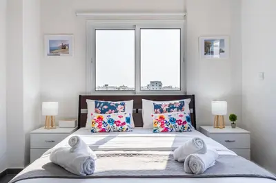 a bedroom with a bed with pillows and two windows at Sonic 2-Bedroom Apartment in Larnaka