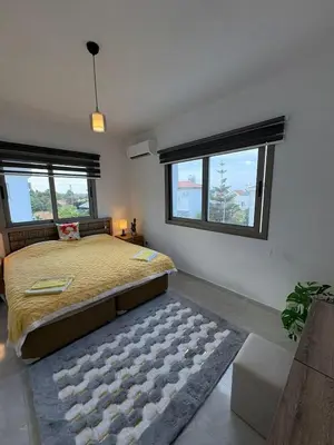 a bedroom with a large bed and two windows at Lapta Yellow 1 bedroom in Limassol