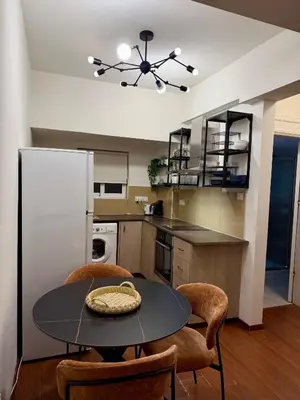 a kitchen with a table and chairs and a refrigerator at Relax Beach Apartment in Larnaka