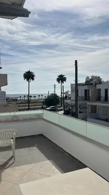 a white bench sitting on top of a building with the beach at Relax Beach Apartment in Larnaka