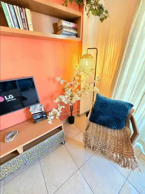 a living room with a tv and a chair at Finikoudes Fabulous Apartment in Larnaka