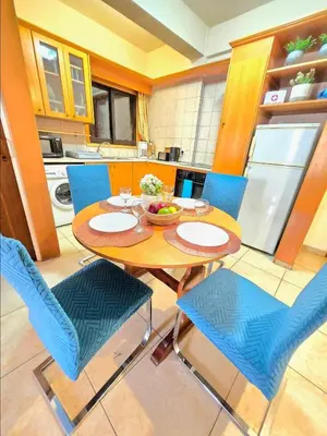 a kitchen with a wooden table and blue chairs at Finikoudes Fabulous Apartment in Larnaka