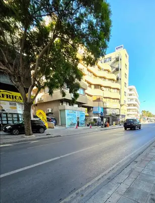 a city street with a tree and a building at Finikoudes Fabulous Apartment in Larnaka