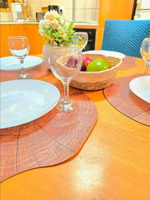 a wooden table with plates and glasses and a bowl of fruit at Finikoudes Fabulous Apartment in Larnaka
