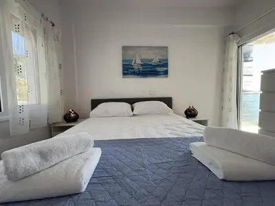a white bedroom with a large bed with two chairs at Cozy beachfront gem with seaview in Limassol