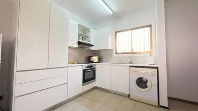 a kitchen with white cabinets and a washing machine at SundyBeach Beachfront 2Bdr Dhekelia in Larnaka