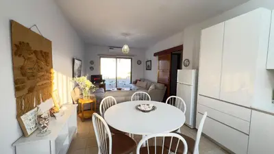 a kitchen and living room with a white table and chairs at SundyBeach Beachfront 2Bdr Dhekelia in Larnaka