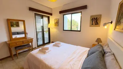 a bedroom with a bed and a table and windows at SundyBeach Beachfront 2Bdr Dhekelia in Larnaka