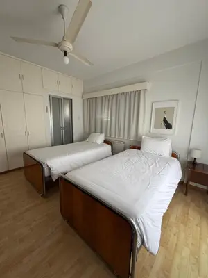 a bedroom with two beds and a ceiling fan at Ellados in Strovolos