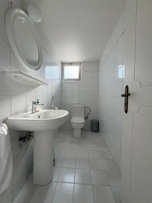 a white bathroom with a sink and a toilet at Ellados in Strovolos