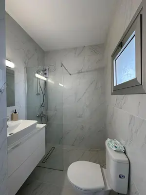 a white bathroom with a toilet and a sink at Seaside Studio in Limassol