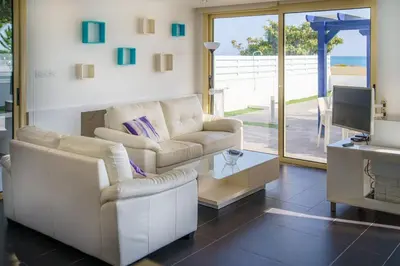 a living room with a couch and a table and a tv at Villa Waves in Mazotos