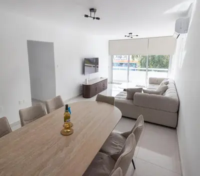 a living room with a wooden table and chairs at Maestro Family - Apartment in Larnaka