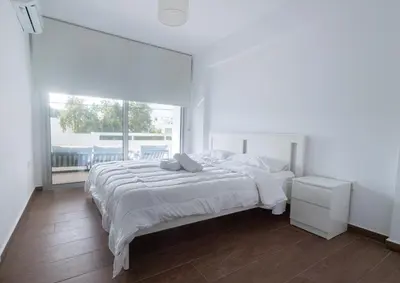 a white bedroom with a large bed and a window at Maestro Family - Apartment in Larnaka