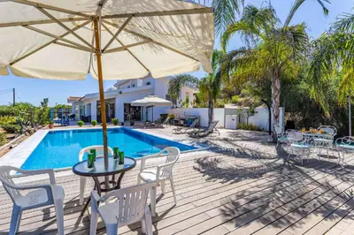 a patio with a table and an umbrella and a pool at Marina Heights Villa in Protaras