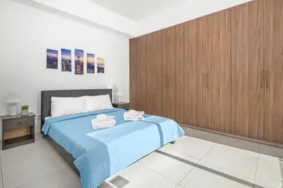 a bedroom with a blue bed and wooden cabinets at Downtown 1 Bedroom City Apartment in Larnaka