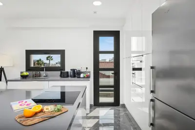a white kitchen with a cutting board on a counter at Noir Luxury Residences by Nomads in Limassol