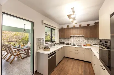a kitchen with white cabinets and a dining room with a table at Maison du Mont in Kalopanayiotis