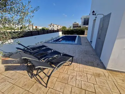 a group of chairs sitting next to a swimming pool at Sunshine Villa Kapparis in Paralimni