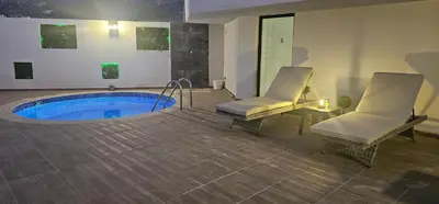 a room with a pool with two chairs and a table at Girne Merkezde Geniş Teraslı Havuzlu Daire in Alsancak