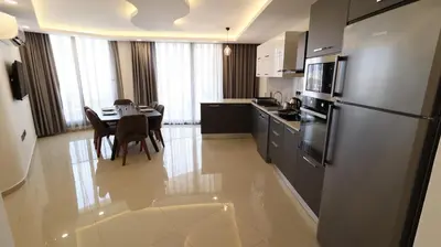 a kitchen and dining room with a table and a refrigerator at Girne Merkezde Geniş Teraslı Havuzlu Daire in Alsancak