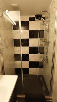 a bathroom with a shower with a black and white checkered wall at Girne Merkezde Geniş Teraslı Havuzlu Daire in Alsancak