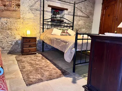 a bedroom with a bed and a stone wall at Charming 3-Bedroom Cottage in Heart of Vasa Koilaniou in Vasa Kilaniou