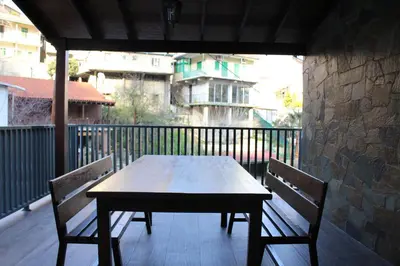 a wooden table and two chairs on a balcony at To Petrino 2 Apartment -Authentic Comfort in the Heart of Kalopanayiotis in Kalopanayiotis