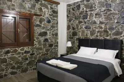 a bedroom with a large bed with a stone wall at To Petrino 2 Apartment -Authentic Comfort in the Heart of Kalopanayiotis in Kalopanayiotis