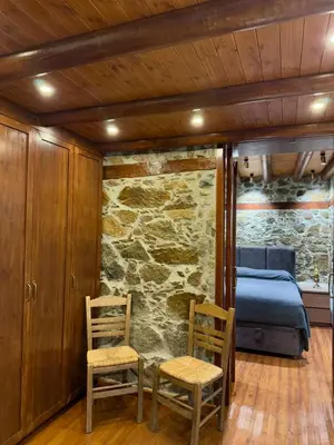 a bedroom with two chairs and a bed and a stone wall at To Petrino 4 Studio- Nature, Comfort & Tradition Under One Roof in Kalopanayiotis
