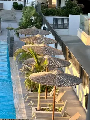 a row of straw umbrellas next to a swimming pool at Fall In Paradise in Paralimni