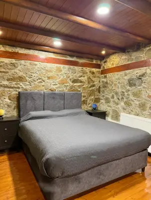 a bedroom with a bed in a stone wall at To Petrino 5 -Apartment- Nature, Comfort & Tradition Under One Roof in Kalopanayiotis