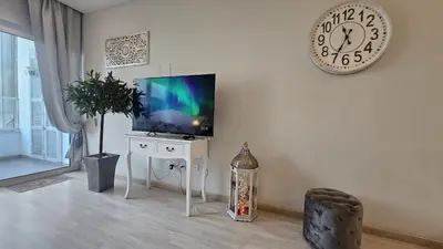 a living room with a tv and a clock on the wall at STAY Armonia Central Suite in Nicosia