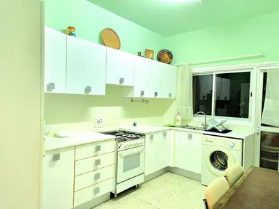 a kitchen with white cabinets and a washer and dryer at Breathtaking Beachfront Apartment in Makenzy in Larnaka