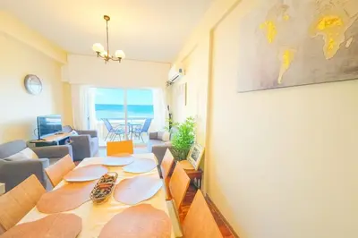 a dining room with a table and a living room at Breathtaking Beachfront Apartment in Makenzy in Larnaka