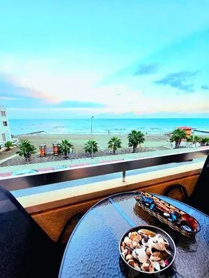 a table with a bowl of food and a view of the beach at Breathtaking Beachfront Apartment in Makenzy in Larnaka