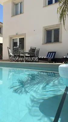 a pool with chairs and a table and a house at Townbeach Villa with Private Pool in Voroklini