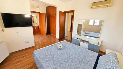 a room with a bed and a television and a table at Townbeach Villa with Private Pool in Voroklini