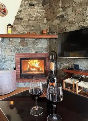 two glasses of wine on a table in front of a fireplace at Kyperounta Heights - Breathtaking View in Kyperounda