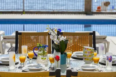 a table with plates and glasses of orange juice and flowers at Meneou Beachfront Villa Sunset in Pervolia