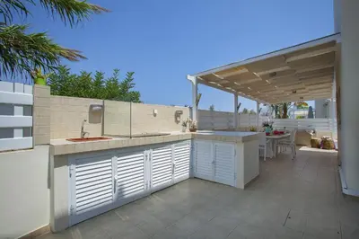 an outdoor kitchen with a sink and a patio at Villa Posidonas 3 in Protaras