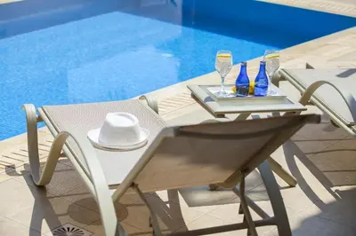 a table with two glasses and wine glasses on it next to a pool at Villa Posidonas 3 in Protaras