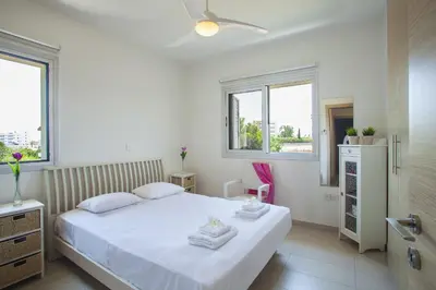 a bedroom with a white bed and two windows at Villa Posidonas 3 in Protaras